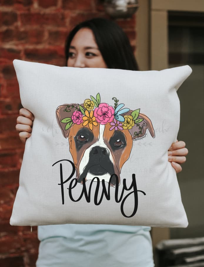 A square pillow with a whimsical drawing of a boxer dog with a flower crown